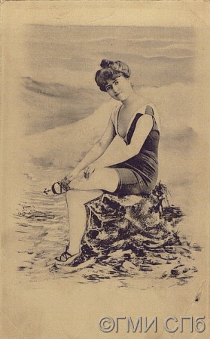 Молодая женщина в купальном костюме, сидящая на камне
